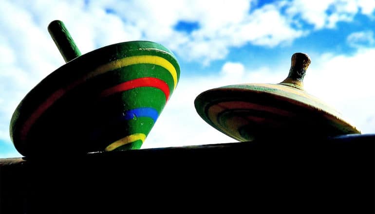 Two spinning tops are covered in shadow against a blue cloudy sky