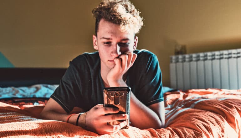 teen on bed looking at phone