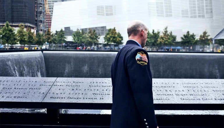 A firefighter looks down at the names carved in the black marble 9/11 memorial in New York