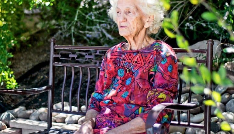 elderly person sits on bench outdoors