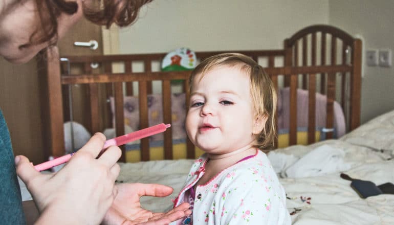 adult gives baby liquid medicine