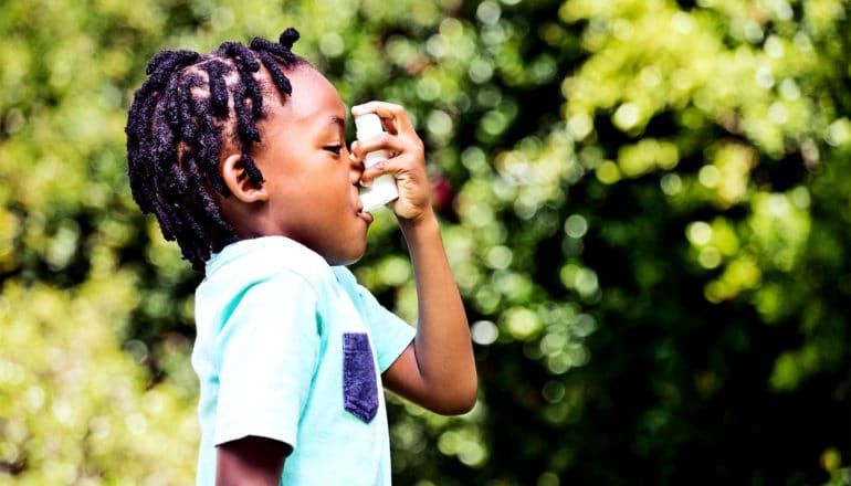 A young boy with asthma uses an inhaler