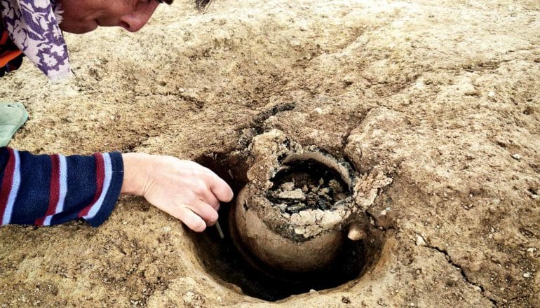 A person reaches over to a partially buried urn