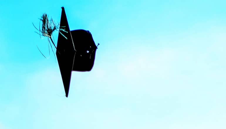 A graduate's cap sails through the blue sky