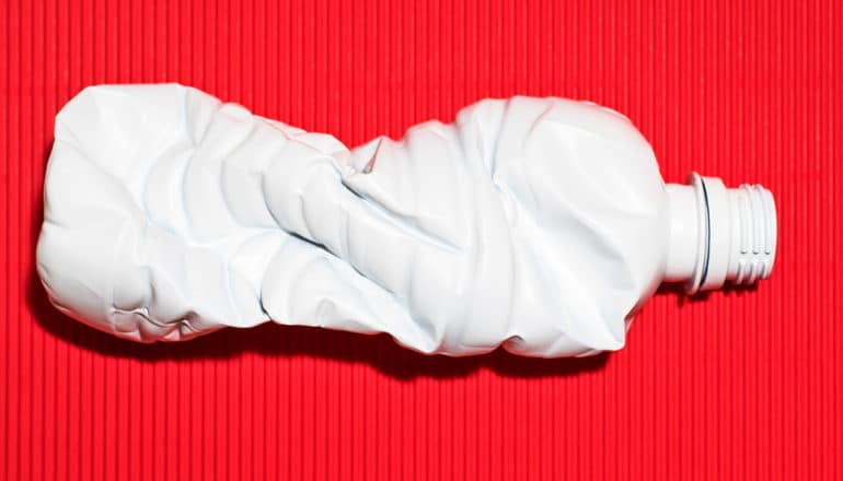 white and crumpled plastic bottle on red background