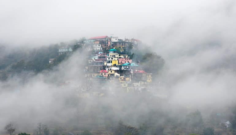 brightly painted houses on mountain through fog