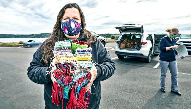 A woman wearing a homemade face mask holds a stack of other homemade masks