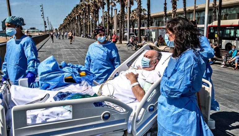 Doctors take a patient on a bed outside to look out at the beach