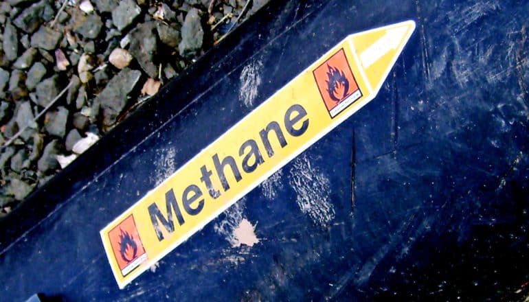 A methane pipe has an arrow-shaped sticker on it labeling the pipe as one for methane