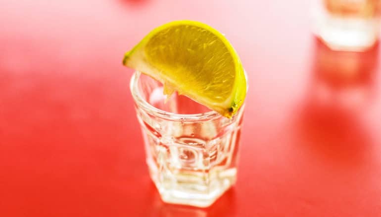 lime wedge on shot glass on red surface