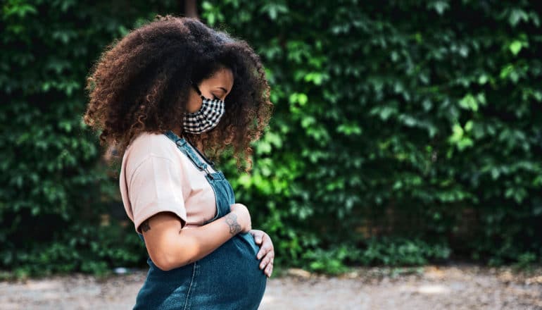 pregnant woman wears mask outdoors