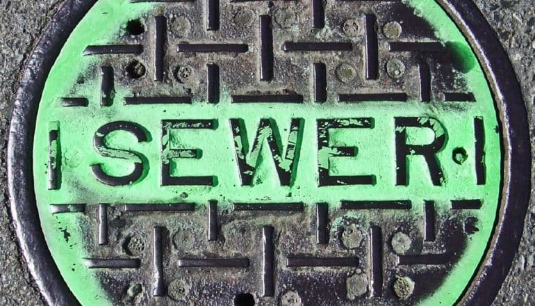 manhole cover says "sewer" with green paint