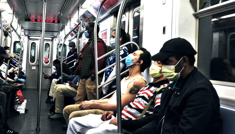 Subway riders in New York City all wearing masks, but sitting closely together