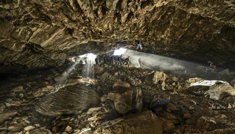 people and shafts of light enter large cave