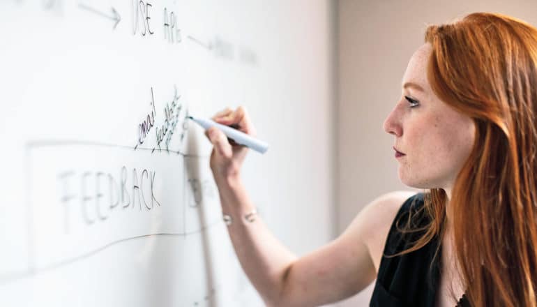 person writes on white board