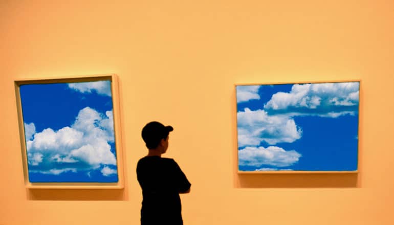 teen looks at two framed images of clouds in gallery