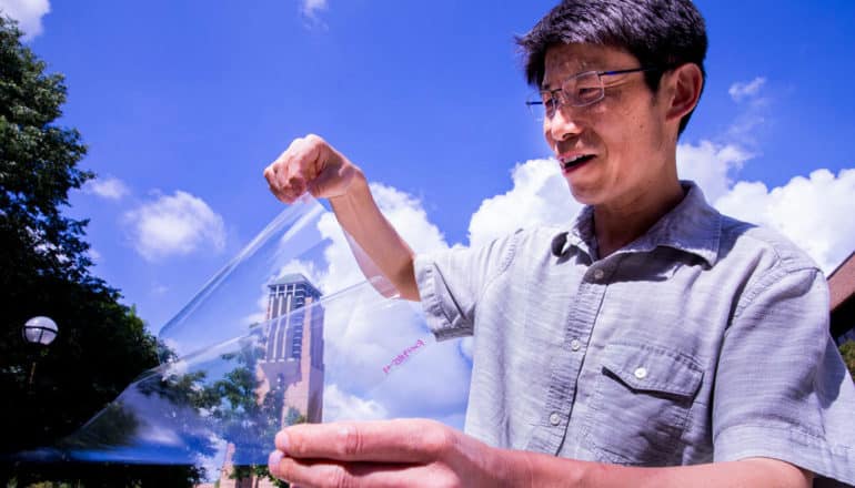 person holds clear plastic sheet outdoors