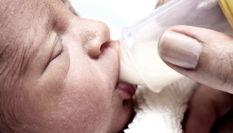 A premature baby drinks milk from a bottle