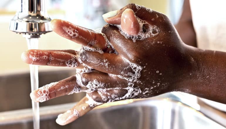 A young woman washes her hands