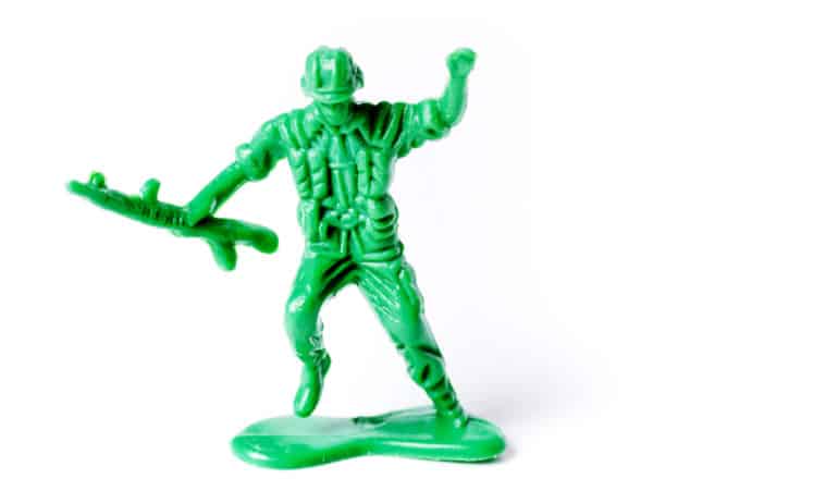 A green army man toy raises his arm as if to say "Charge!" against a white background