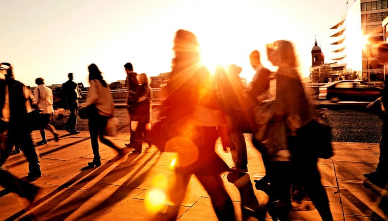 People walk through a city as the hot sun beats down on them