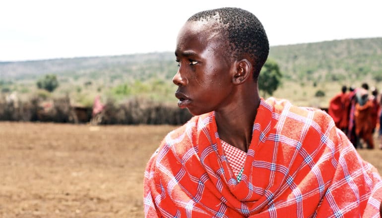 A young man from the Masai people in Kenye wears a bright orange wrap