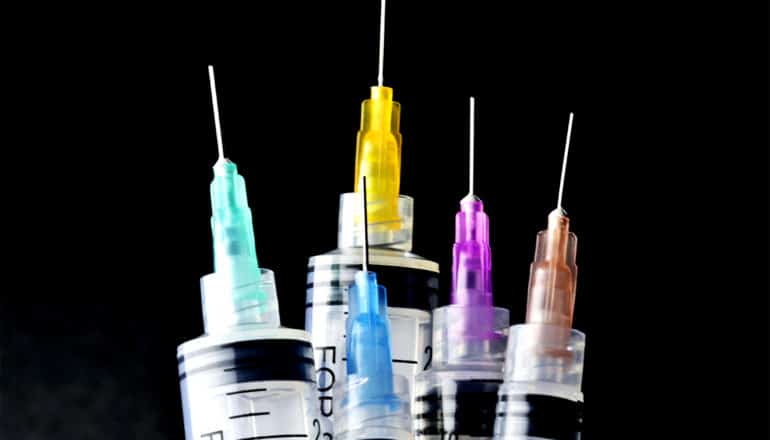 A group of syringes against a black background