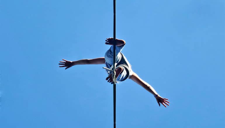 A person walks across a tight rope, as seen from below