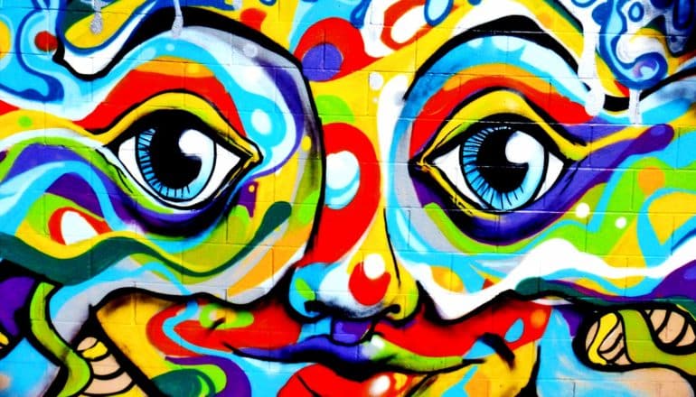 A painting on a white wall of a colorful, distorted face