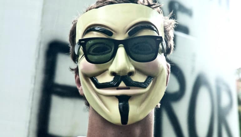 A man wears Guy Fawkes mask and sunglasses