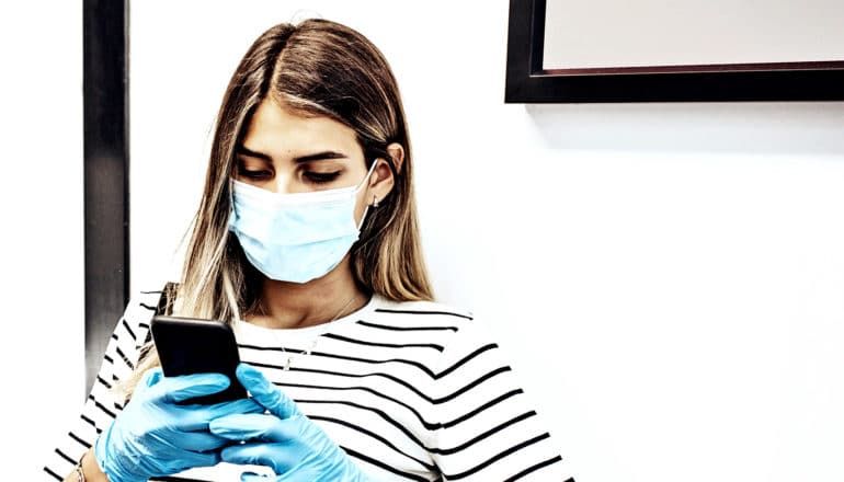 A woman in a medical mask sits in a doctor's waiting room