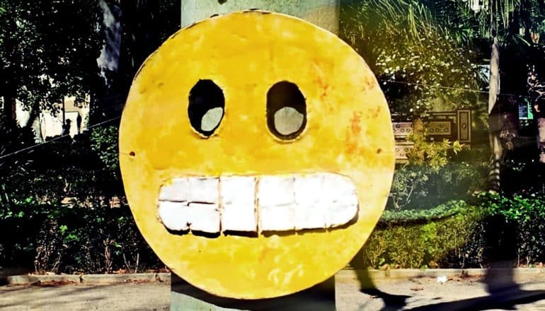 A scared emoji with clenched teeth hangs on a telephone poll