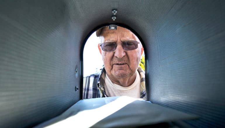 A man looks into his mailbox with a concerned look on his face