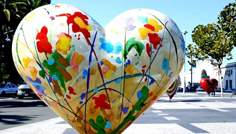 A sculpture of a heart has brightly colored paint all over it's white base