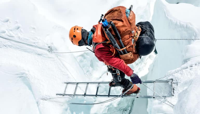 A climber walks across a metal ladder over a gorge on Mount Everest