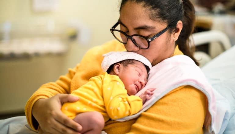 mom kissing newborn baby on head