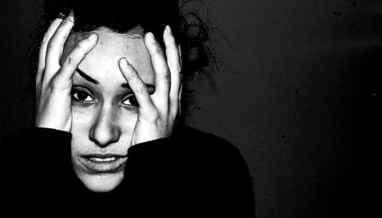 A young woman holds her head in her hands in stress