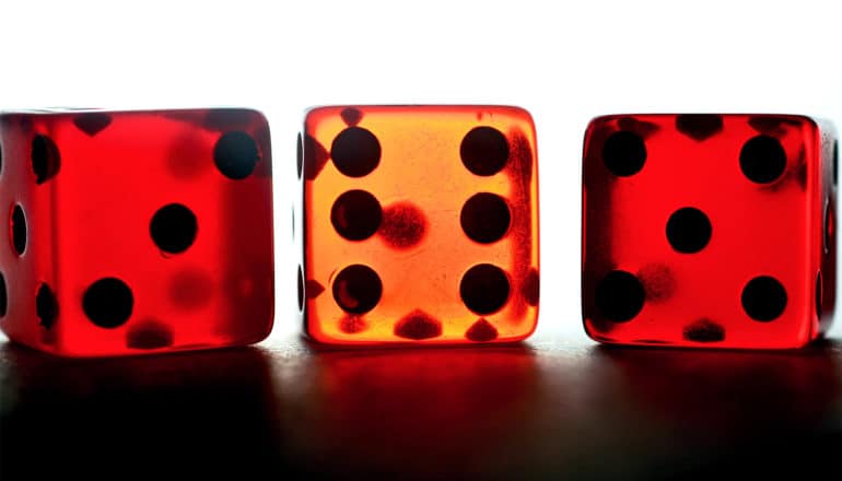 Three red plastic dice have light shining through them from behind