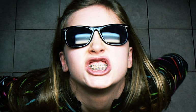 tween in sunglasses bares teeth with braces