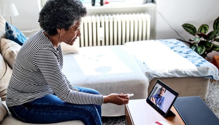 A woman talks to her doctor via a telehealth call on her iPad