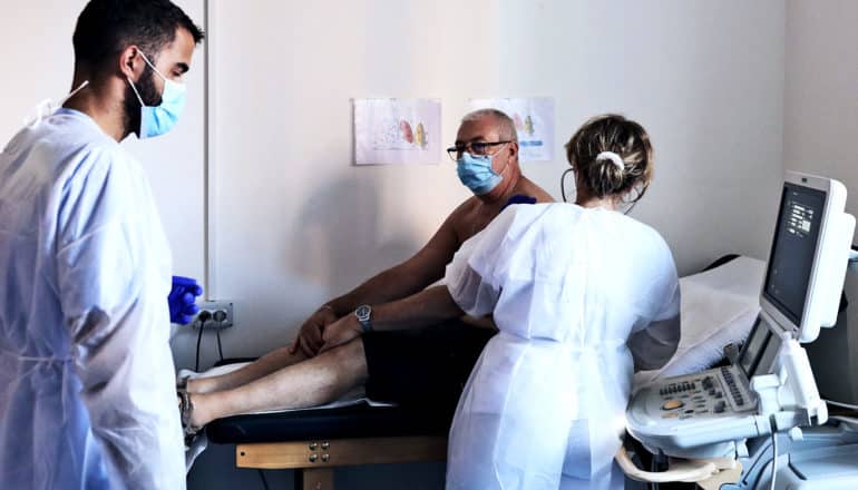 A doctor gives a patient in a face mask an ultrasound