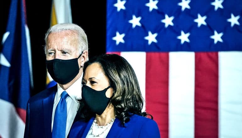 Joe Biden and Kamala Harris wear black face masks as they stand in front of the American flag