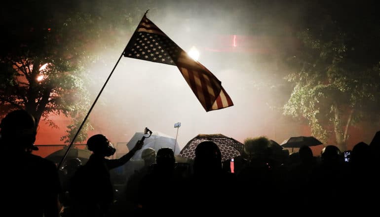 US flag over protest crowd