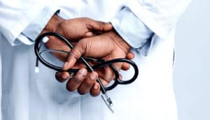 A doctor holds a stethoscope behind their back