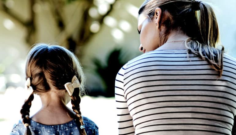 A mother listens to her daughter while they sit outside