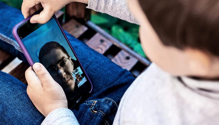 A young boy speaks to his father via Facetime on his phone