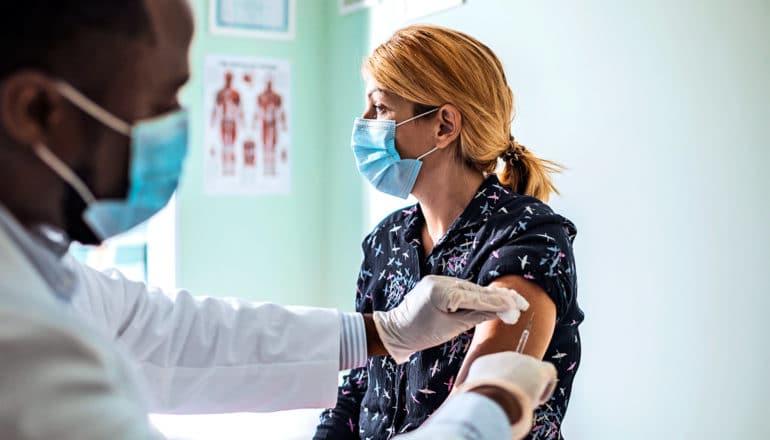 A woman wears a blue mask as she gets a flu shot