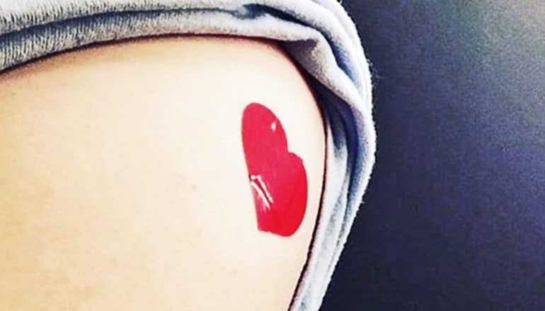 A person has a heart-shaped sticker on their arm with their sleeve rolled up