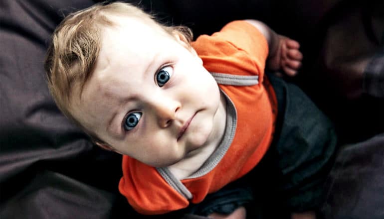 A toddler looks up at the camera with a worried look