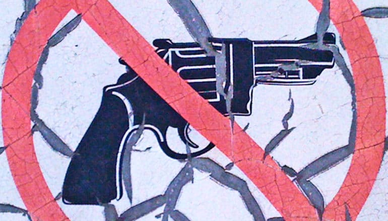 A painting on a wall of a handgun with a red circle and a slash over it